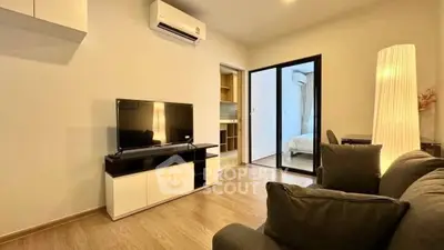 Modern living room with sleek furniture and open view to bedroom, featuring a stylish floor lamp and air conditioning.
