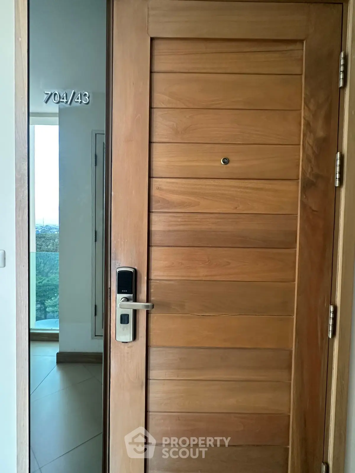 Modern apartment entrance with wooden door and digital lock, offering security and style.