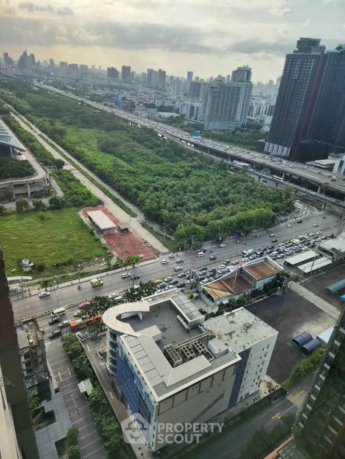 Stunning cityscape view from high-rise building overlooking lush green park and urban skyline.