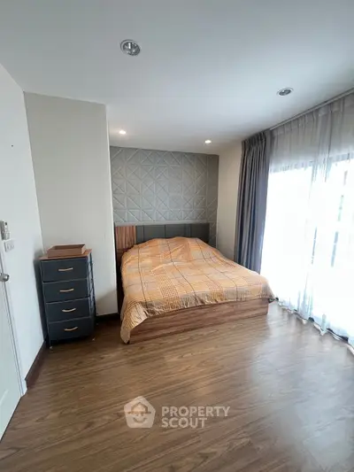 Spacious bedroom with modern decor and large window for natural light