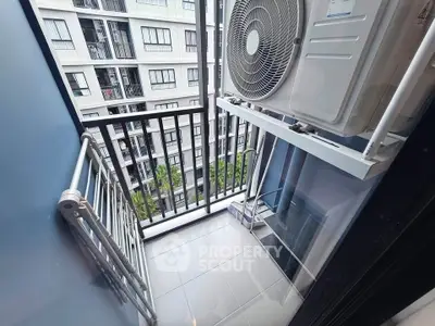 Compact balcony with air conditioning unit and view of modern apartment building.