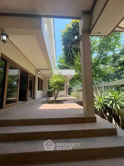 Spacious outdoor patio with lush greenery and modern architecture, perfect for relaxation and entertaining.