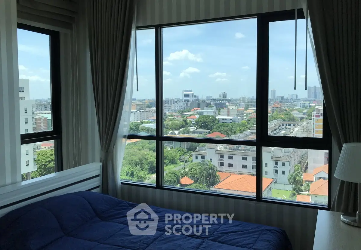 Spacious bedroom with large windows offering stunning city views, perfect for urban living.