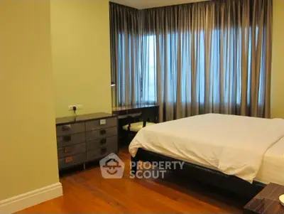 Spacious bedroom with elegant wooden flooring and large windows for natural light.