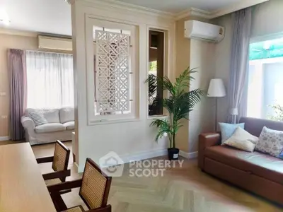 Spacious living room with elegant decor and natural light, featuring a cozy sofa and stylish chairs.