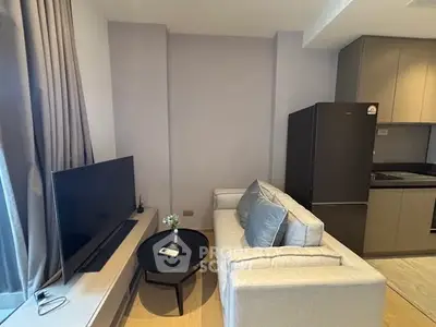 Modern living room with sleek TV setup and compact kitchen area.