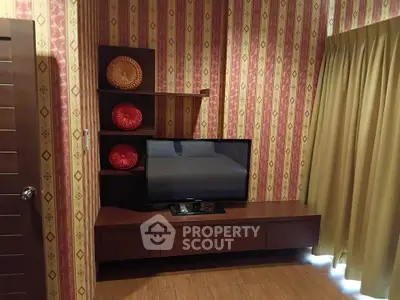 Charming living room with stylish wallpaper and modern TV setup, perfect for cozy evenings.