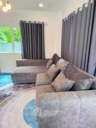 Stylish living room with modern gray sectional sofa and elegant curtains, perfect for cozy gatherings.