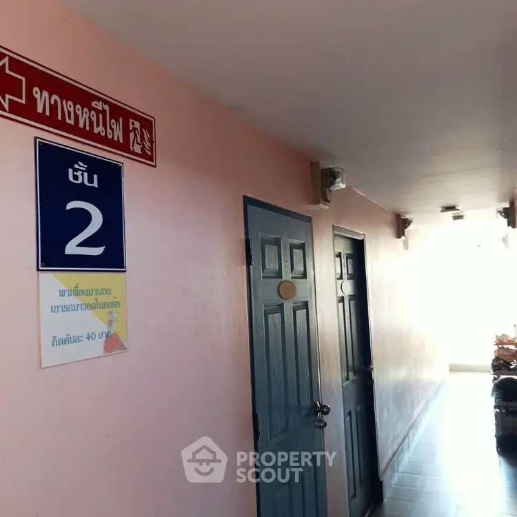 Corridor with blue doors and emergency exit sign in residential building