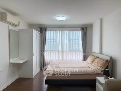 Spacious bedroom with modern furnishings and large window for natural light.