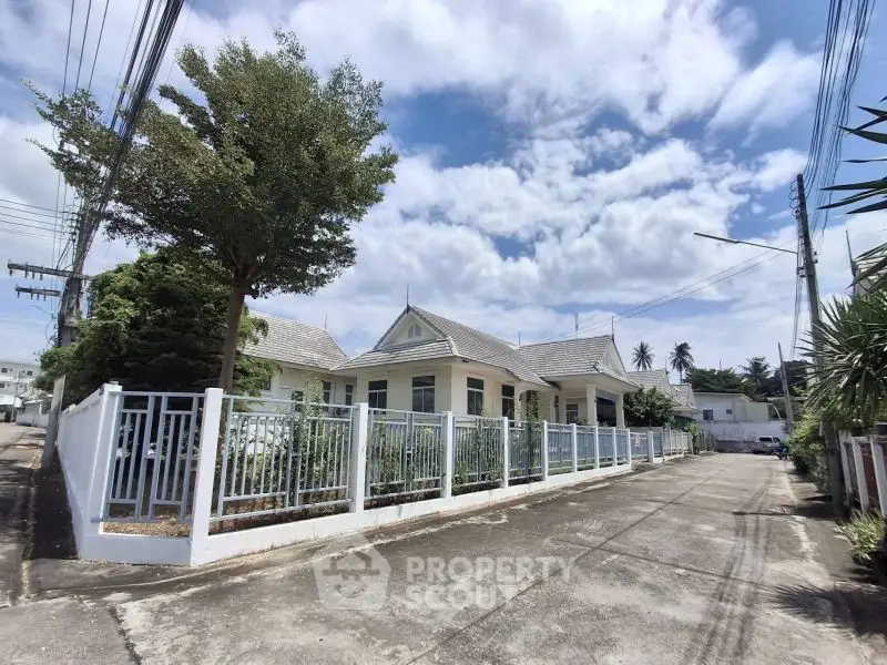 Charming suburban house with a spacious yard and white picket fence under a clear blue sky.
