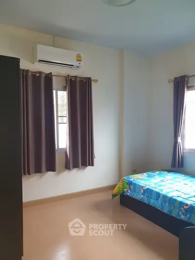 Cozy bedroom with air conditioning and colorful bedding in a well-lit space.