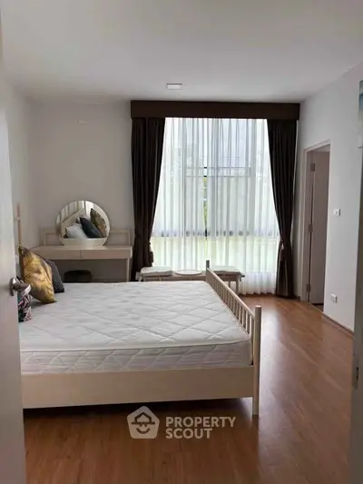 Spacious bedroom with elegant decor and large window for natural light.