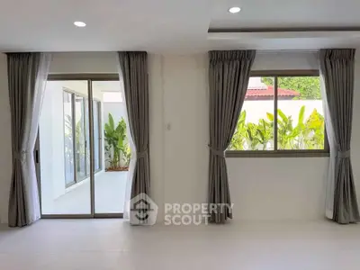 Spacious living room with sliding glass doors leading to a lush garden patio.