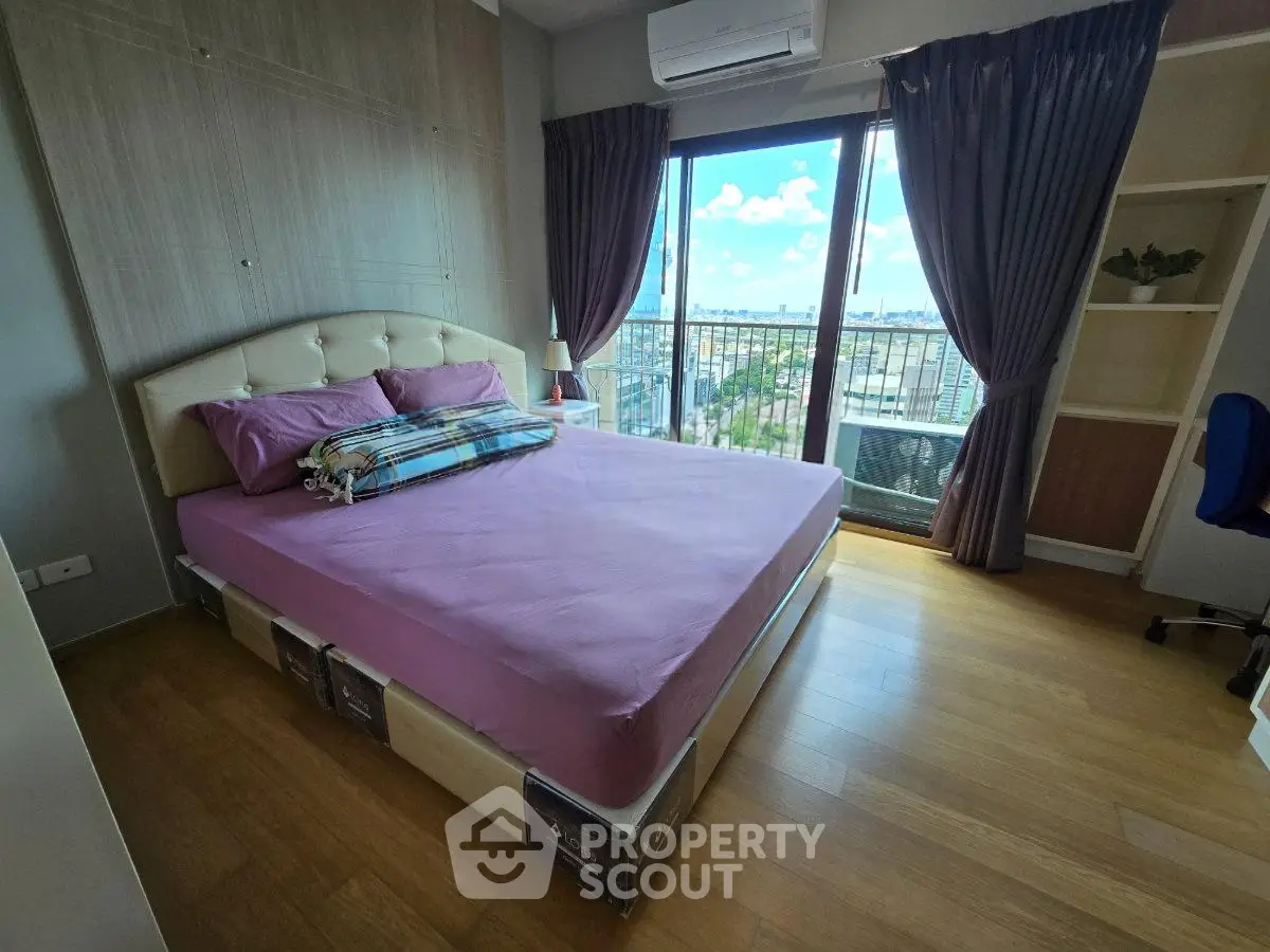 Spacious bedroom with large window and city view, featuring a comfortable bed and modern decor.