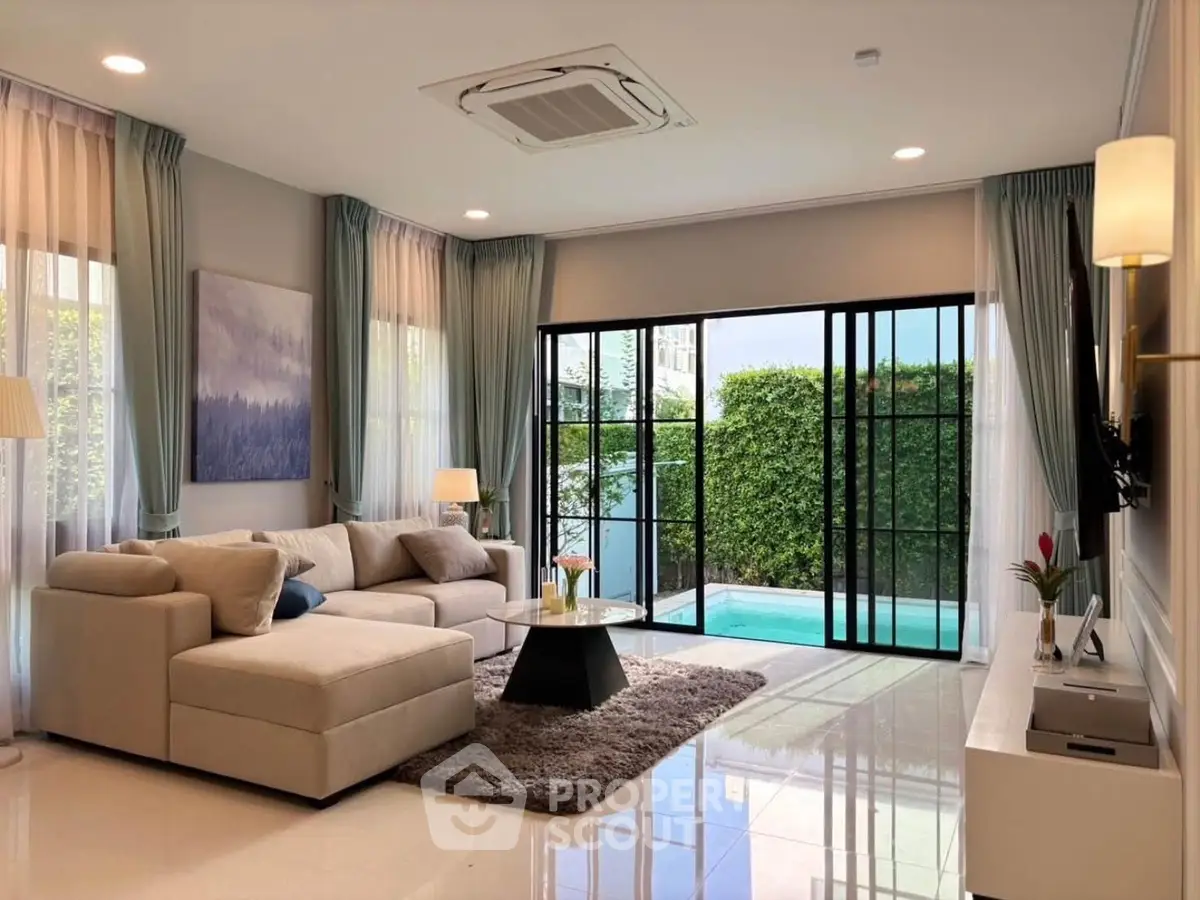 Luxurious living room with pool view, featuring elegant decor and ample natural light.