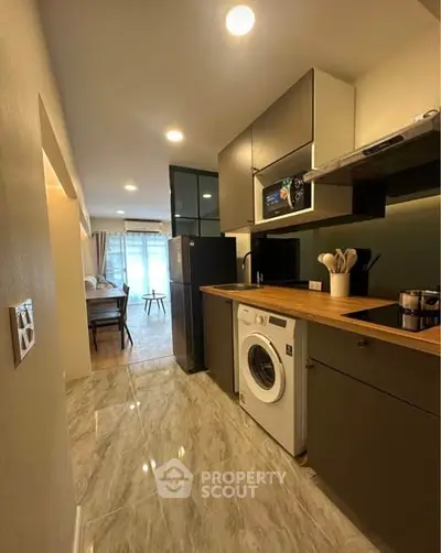 Modern kitchen with sleek appliances and open layout leading to dining area.