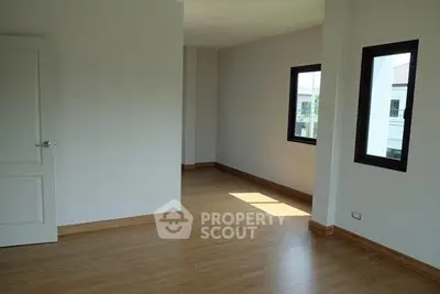 Spacious empty room with wooden flooring and large windows, ideal for customization.