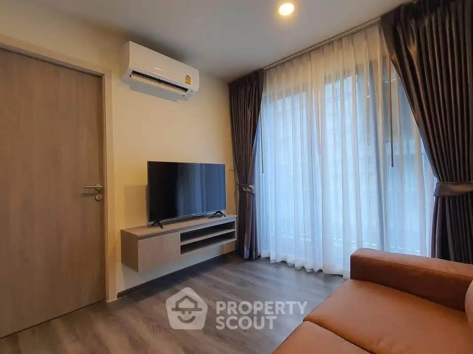 Modern living room with air conditioning and large window, featuring a sleek TV setup and cozy sofa.