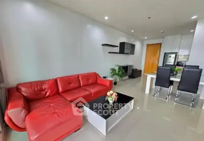 Modern living room with red leather sofa and sleek dining area in open layout apartment.