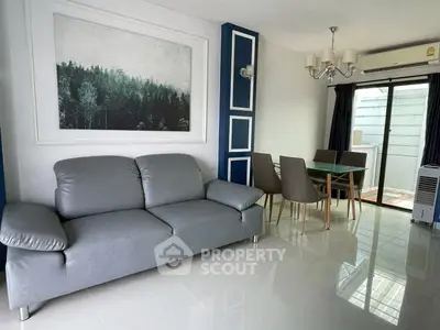 Modern living room with sleek gray sofa and elegant dining area, featuring stylish decor and natural light.