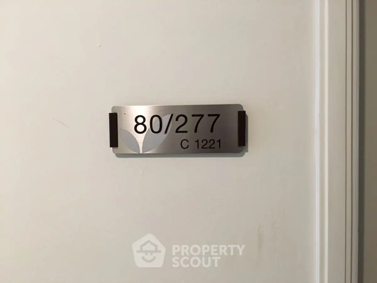 Apartment door with unit number 80/277 on a sleek metal plaque.