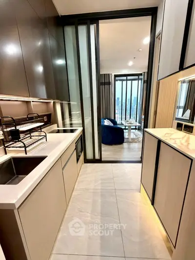 Modern kitchen with sleek cabinetry and open layout leading to a stylish living room with city view.