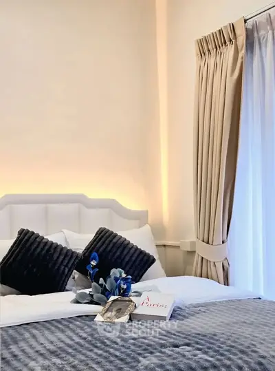 Elegant bedroom with plush bedding and stylish decor, featuring soft lighting and luxurious curtains.