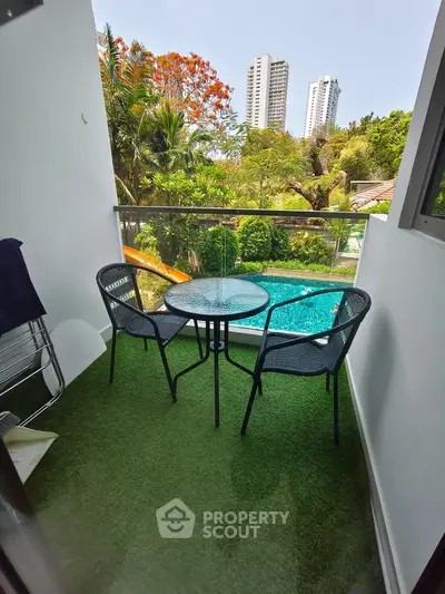 Charming balcony with lush garden view and pool, perfect for relaxation in urban setting.