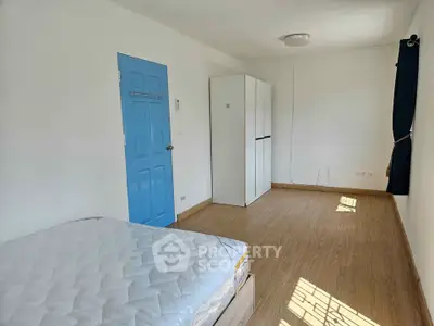 Spacious bedroom with blue door, wardrobe, and natural light.
