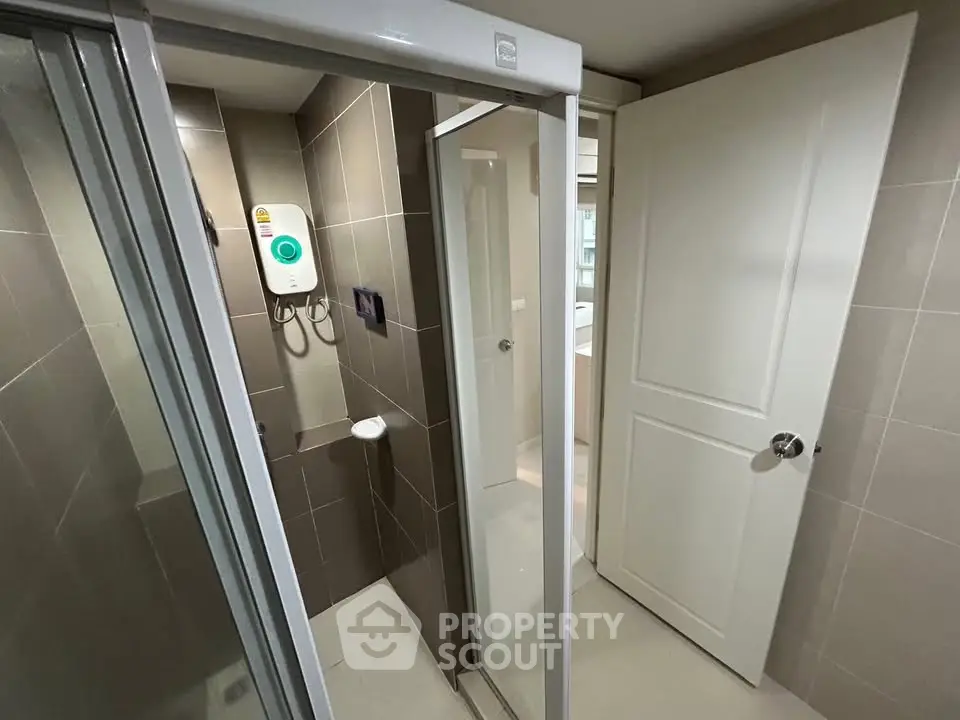 Modern bathroom with sleek shower and water heater in contemporary apartment.