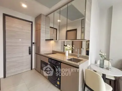 Modern kitchen with integrated appliances and dining area in stylish apartment.