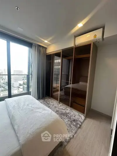 Modern bedroom with city view, featuring sleek wardrobe and cozy decor.