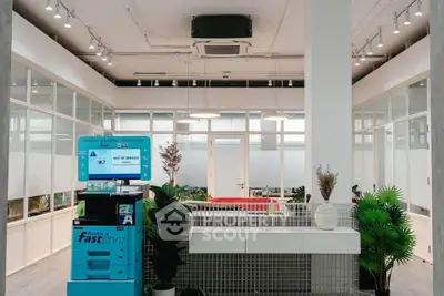 Modern office space with glass partitions and greenery, featuring a fast print station.