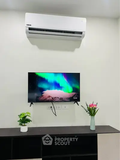Modern living room with air conditioner and wall-mounted TV displaying vibrant aurora.