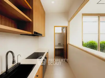 Modern kitchen with sleek design and open layout, featuring wooden cabinets and large windows.