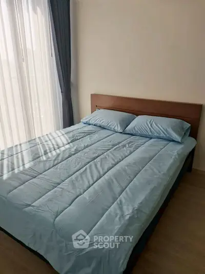Cozy bedroom with natural light and modern furnishings in a stylish apartment.