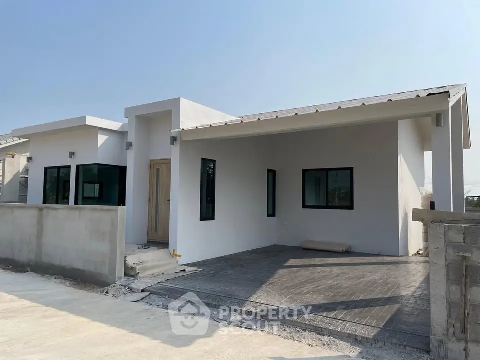 Modern single-story white house with minimalist design and spacious driveway.