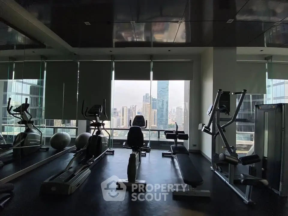 Luxurious high-rise gym with stunning city skyline view, featuring modern fitness equipment and floor-to-ceiling windows.