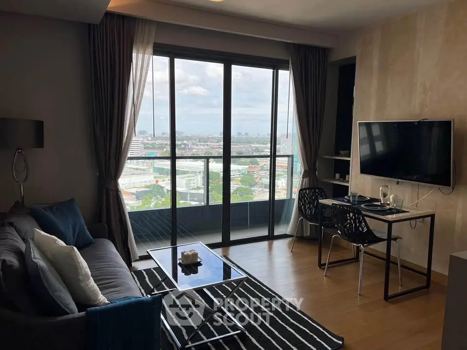 Modern living room with balcony and city view, featuring sleek furniture and large windows.