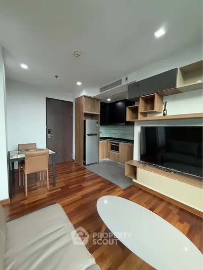 Modern living room with open kitchen, sleek furniture, and wooden flooring in a stylish apartment.
