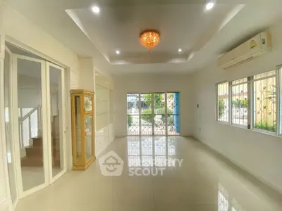 Spacious living room with elegant chandelier and large windows for natural light.