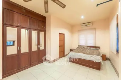 Spacious bedroom with wooden wardrobe and ceiling fan, perfect for comfort and style.