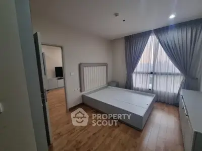 Spacious bedroom with wooden flooring and large window for natural light