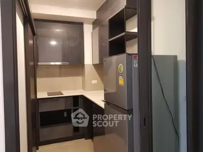 Modern compact kitchen with sleek cabinetry and stainless steel fridge