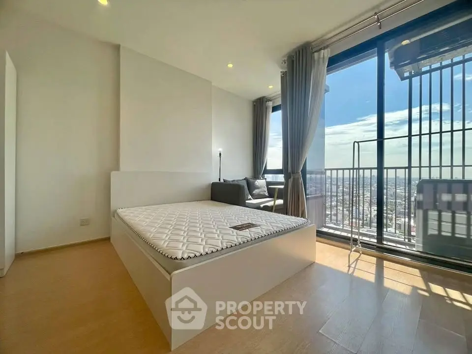 Spacious bedroom with large windows offering stunning city views and abundant natural light.