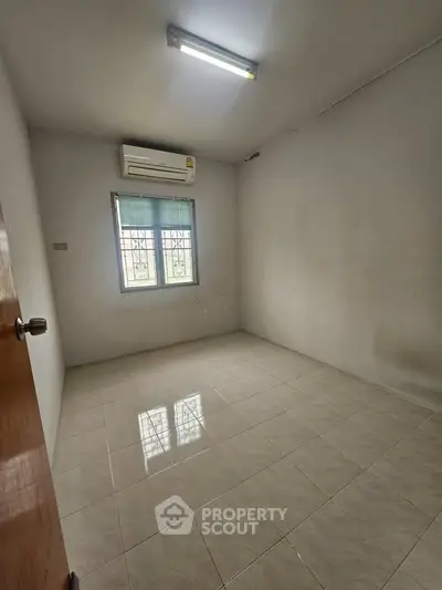 Spacious empty room with tiled floor and air conditioning, ready for customization.