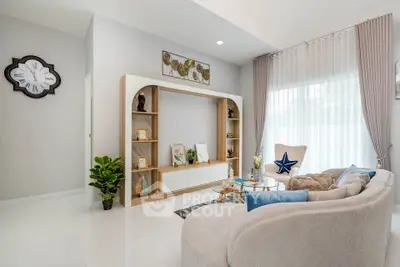 Modern living room with elegant decor and cozy seating area, featuring a stylish bookshelf and large window.