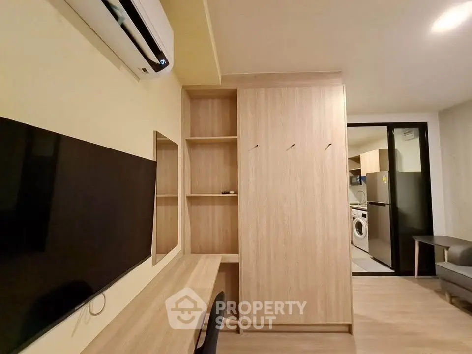 Modern apartment interior with built-in wooden storage and wall-mounted TV, featuring a sleek air conditioning unit.