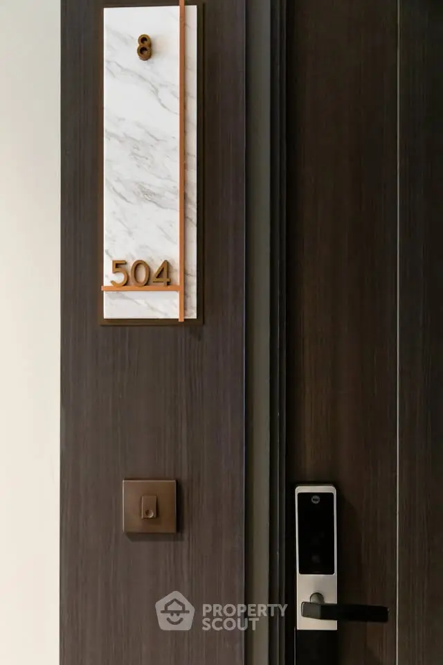 Modern apartment entrance with electronic lock and stylish room number 504 plaque.